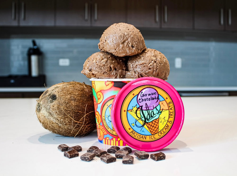 
            
                Load image into Gallery viewer, German chocolate ice cream scoops in an Ida&amp;#39;s Artisan Ice Cream cup alongside a fresh, whole coconut surrounded by chocolate chunks
            
        